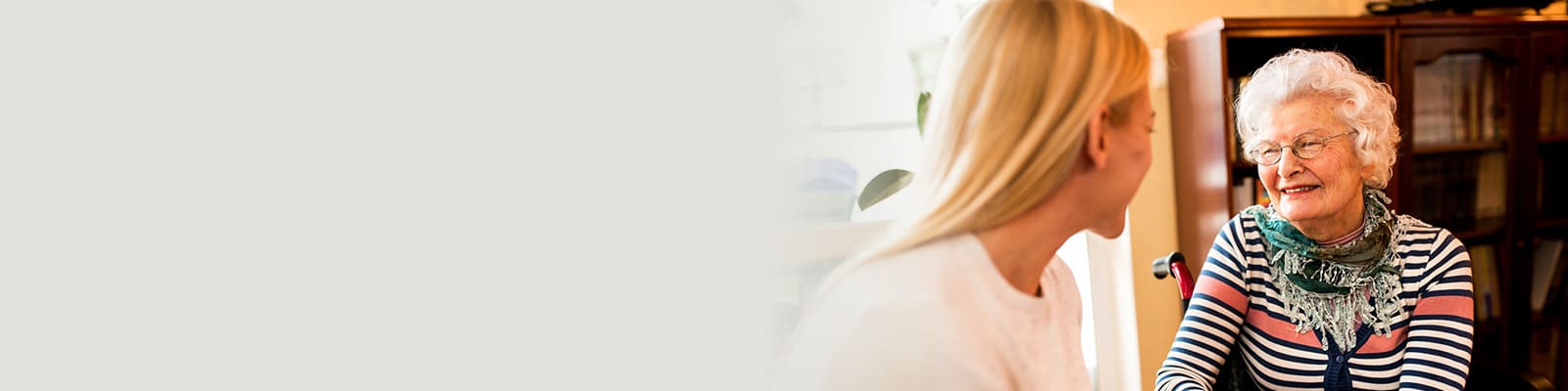 An elderly woman talking to a young lady